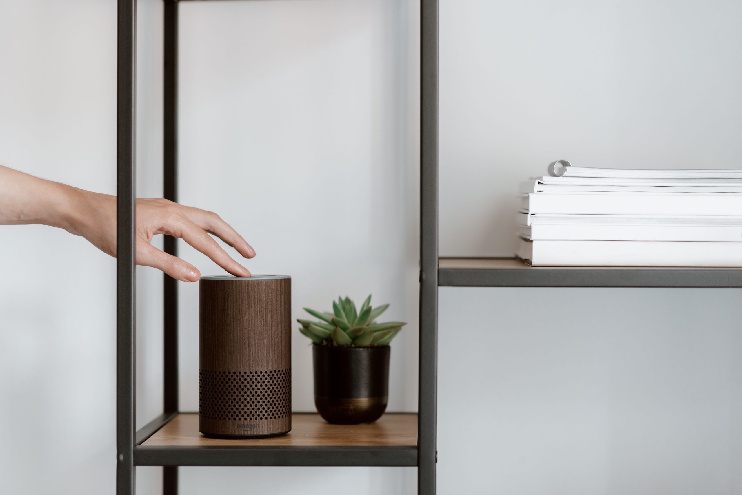 A person reaching for an Amazon Echo smart speaker on a shelf