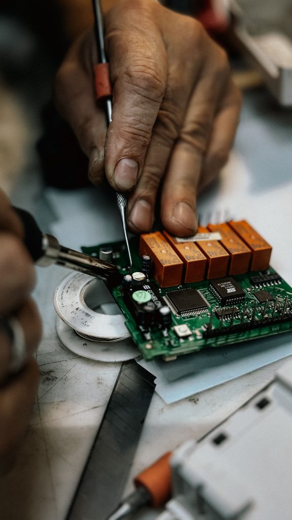 Hands working on an electronic circuit board representing DIY tech setup