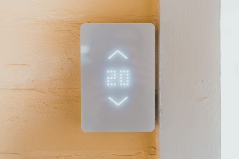Do smart thermostats save money — a modern smart thermostat installed on a wall