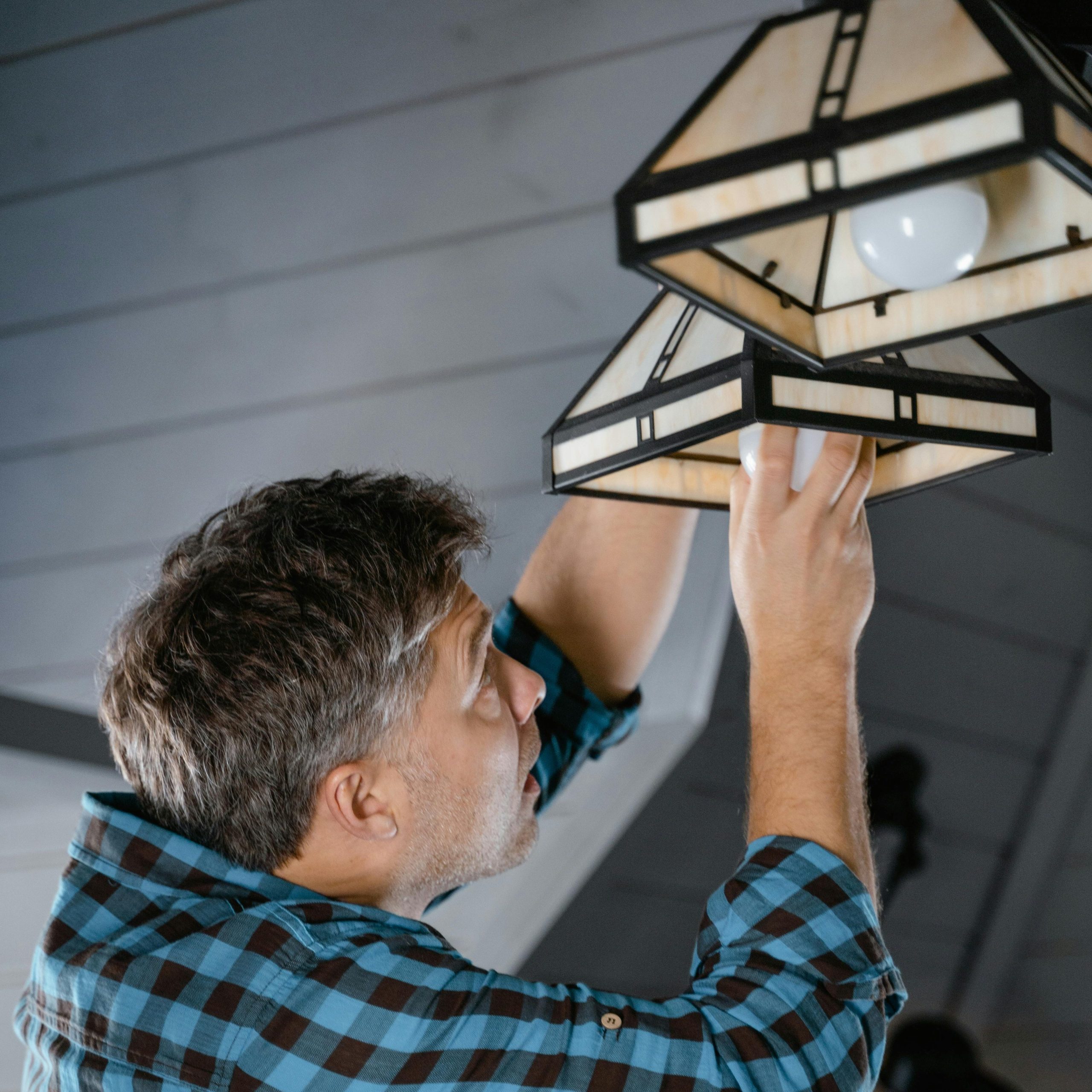 A person installing a light bulb in a multi-bulb ceiling fixture