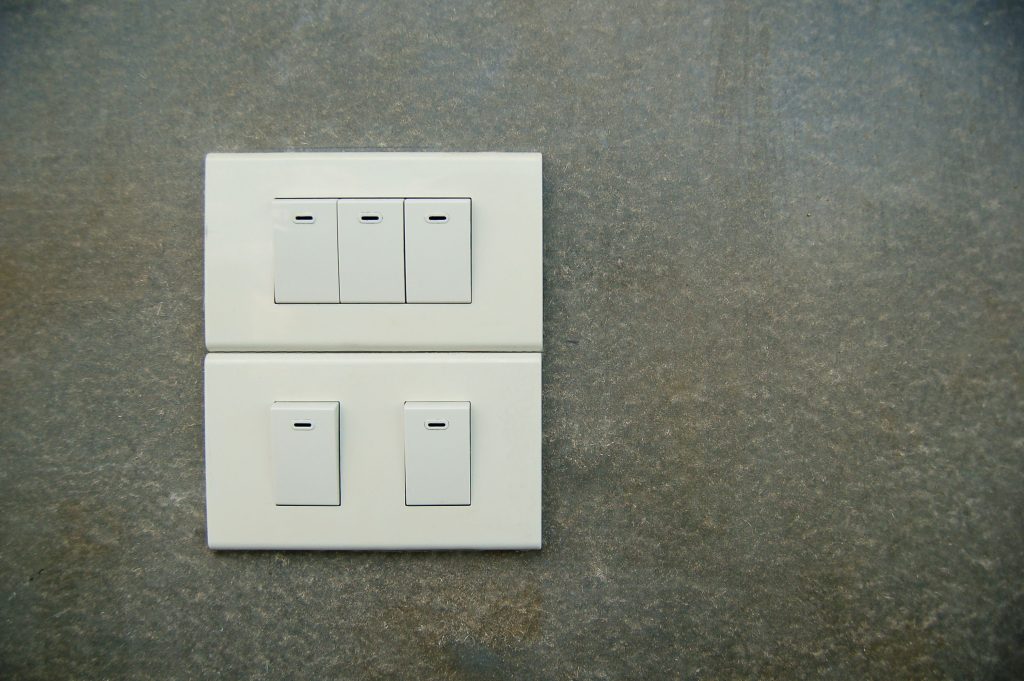 A wall panel of light switches illustrating smart bulbs vs smart switches choices