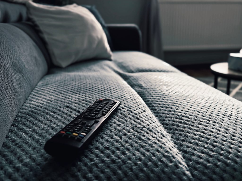 A TV remote on a couch representing the Movie Night smart home routine